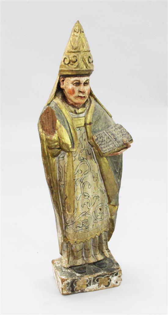 An 18th century Spanish carved and polychrome painted figure of a bishop standing with bible in left hand, 36.5in.